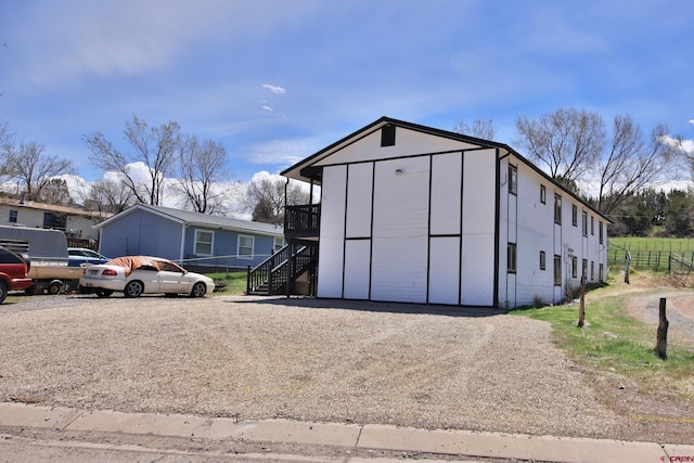 view of outbuilding featuring stairway and fence