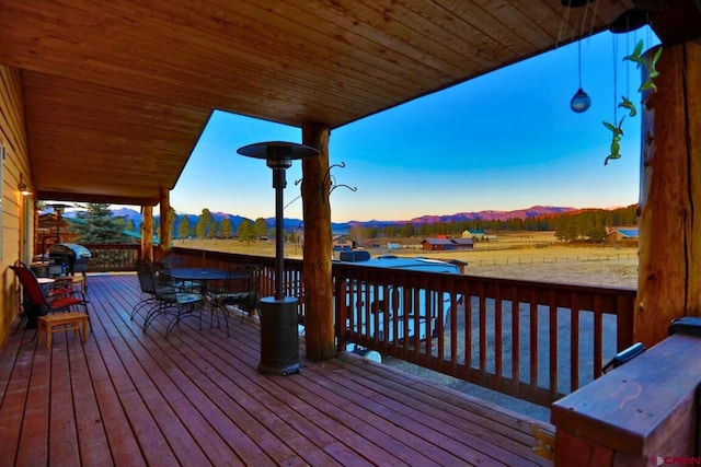 wooden deck with a mountain view and outdoor dining area