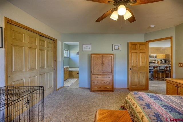 bedroom with light carpet, ensuite bath, a closet, baseboards, and ceiling fan