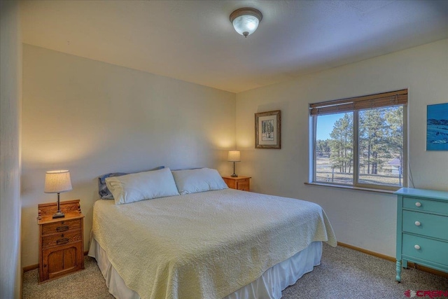 bedroom with baseboards and light carpet