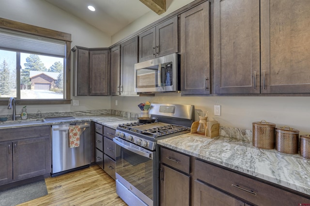 kitchen with a sink, lofted ceiling, dark brown cabinetry, and appliances with stainless steel finishes