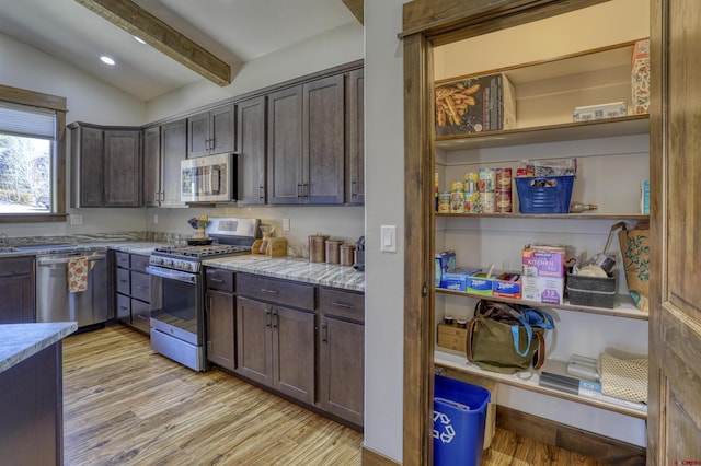 kitchen featuring lofted ceiling with beams, stainless steel appliances, light wood-style floors, and dark brown cabinets