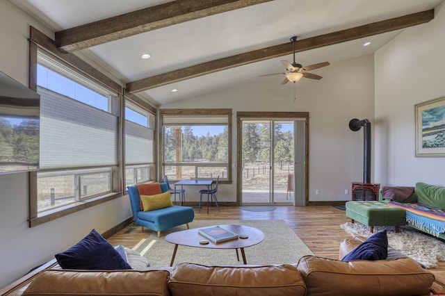 living area with vaulted ceiling with beams, baseboards, recessed lighting, a wood stove, and wood finished floors