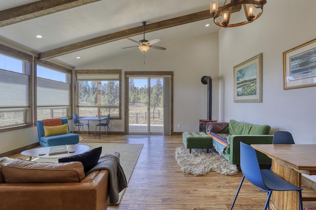 living area with beamed ceiling, baseboards, wood finished floors, and a wood stove