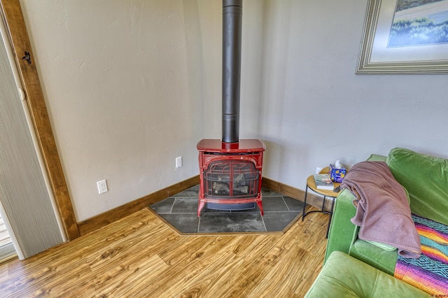 interior details featuring a wood stove, wood finished floors, and baseboards