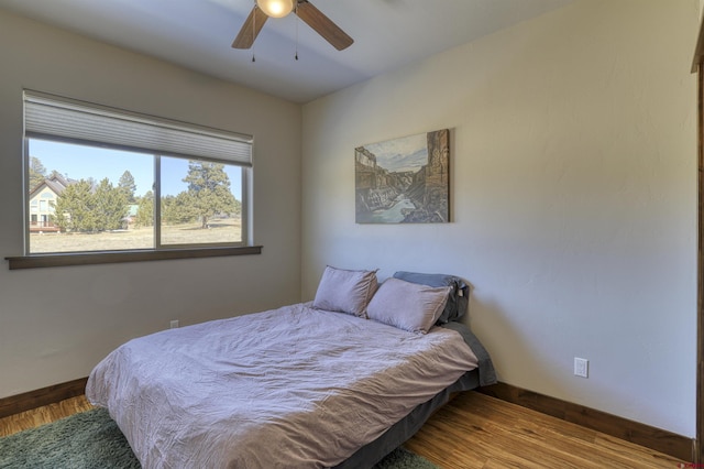 bedroom with ceiling fan, baseboards, and wood finished floors