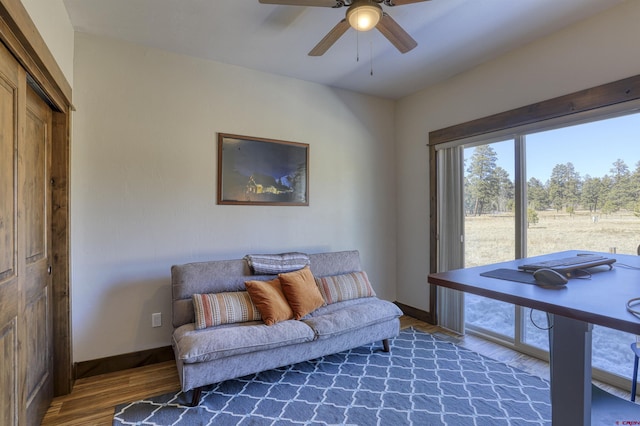 living room featuring baseboards, wood finished floors, and a ceiling fan