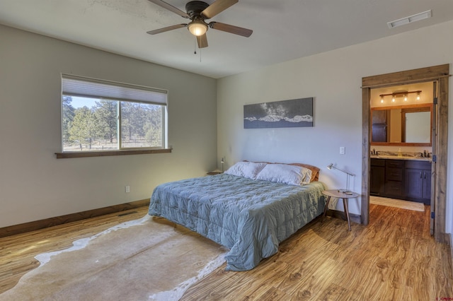 bedroom with visible vents, ensuite bathroom, baseboards, and wood finished floors