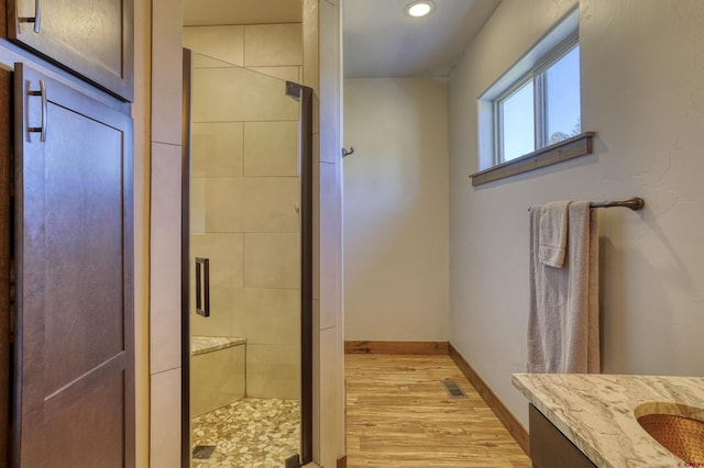 bathroom featuring visible vents, a stall shower, wood finished floors, baseboards, and vanity