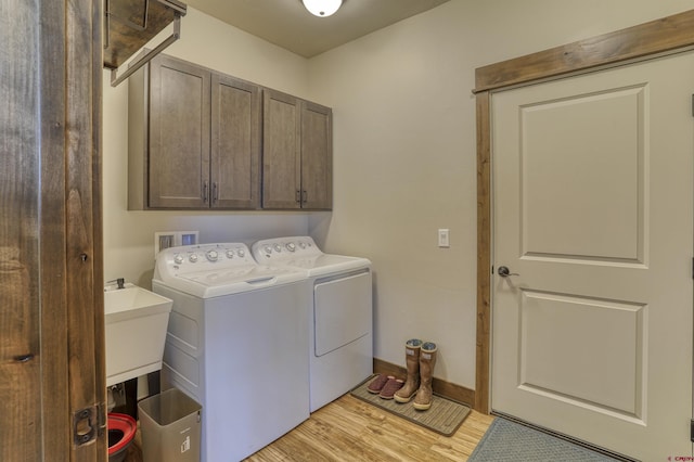 laundry area with washing machine and dryer, cabinet space, baseboards, and light wood finished floors