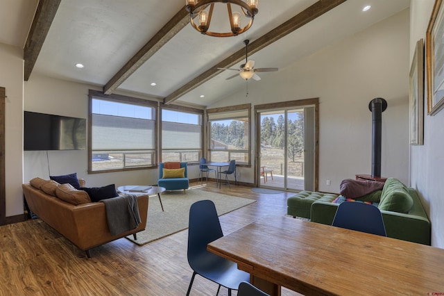 living room featuring a wood stove, vaulted ceiling with beams, wood finished floors, and recessed lighting