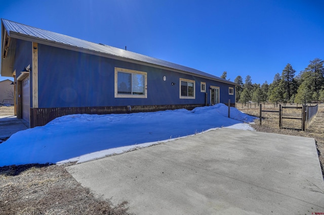 view of front facade featuring metal roof, a garage, and fence