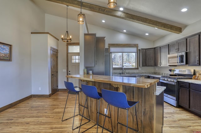 kitchen with stainless steel appliances, dark brown cabinetry, and a breakfast bar area