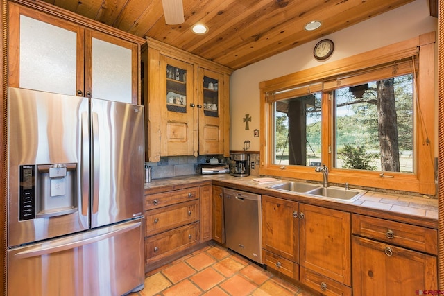 kitchen with a sink, appliances with stainless steel finishes, tile counters, and wood ceiling