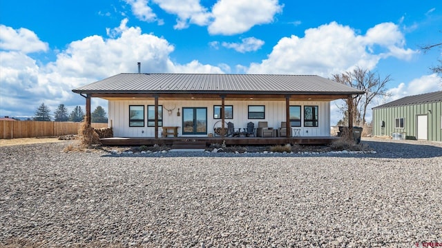 back of property featuring metal roof, board and batten siding, covered porch, and fence