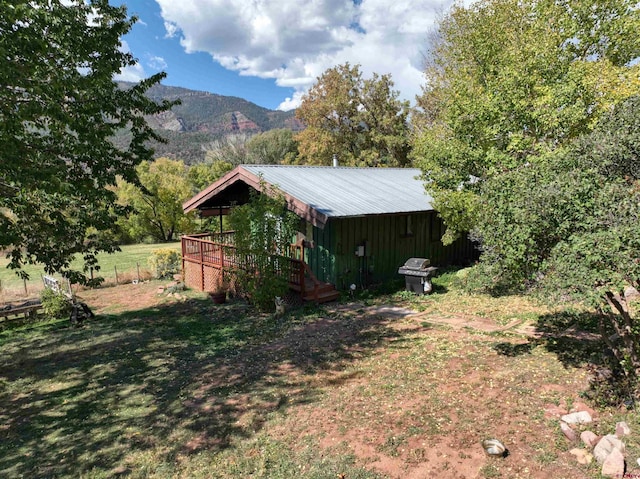 view of yard with a deck with mountain view and fence