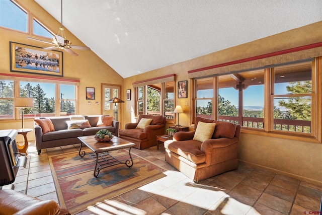 living area with baseboards, a healthy amount of sunlight, high vaulted ceiling, and ceiling fan