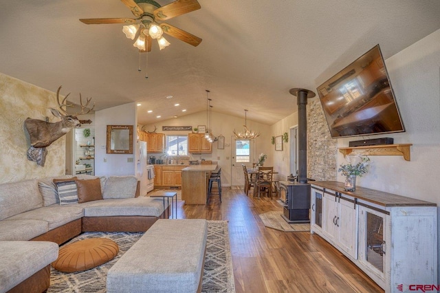 living area featuring lofted ceiling, wood finished floors, and ceiling fan with notable chandelier