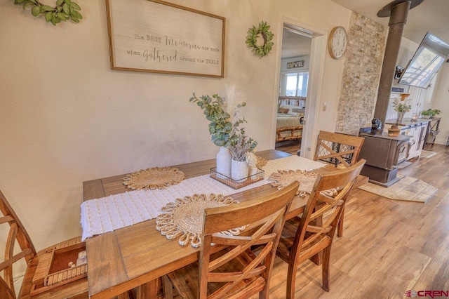 dining space featuring a wood stove and wood finished floors