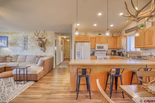 kitchen with light wood-style flooring, a kitchen breakfast bar, open floor plan, white appliances, and a peninsula