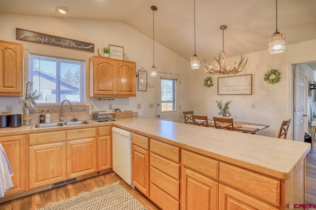 kitchen featuring a sink, a peninsula, white dishwasher, and light countertops