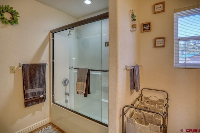 full bath featuring baseboards and shower / bath combination with glass door