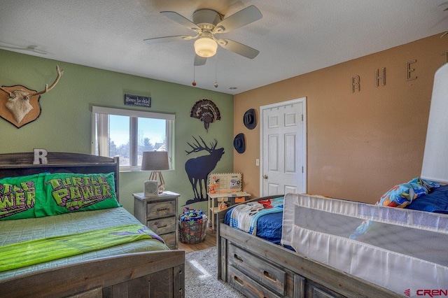 bedroom with a textured ceiling, ceiling fan, and wood finished floors