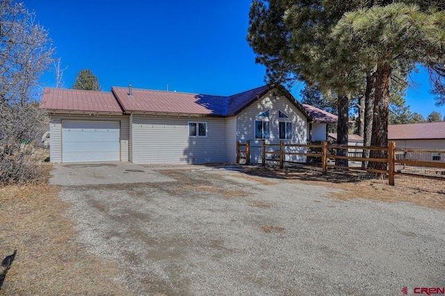 view of front of house with metal roof, a garage, driveway, and fence