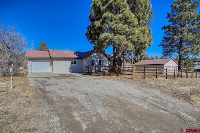 view of front facade with a garage, metal roof, dirt driveway, and fence