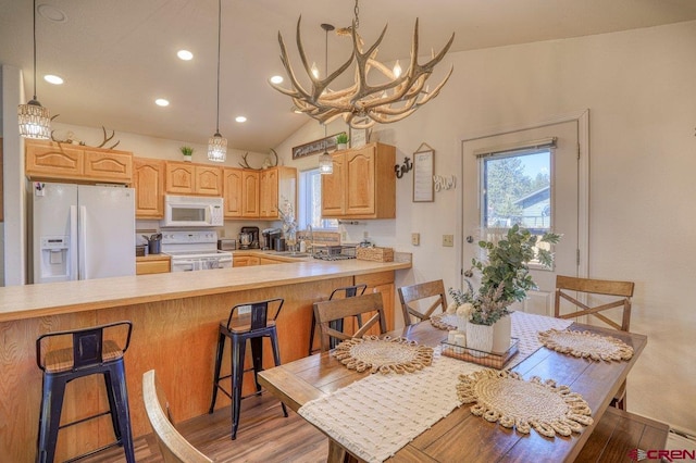 kitchen featuring light brown cabinets, light countertops, a peninsula, white appliances, and a sink