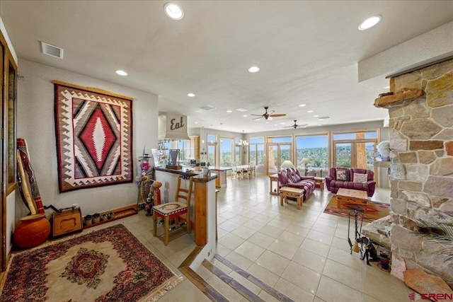 living area with light tile patterned floors, visible vents, a stone fireplace, and recessed lighting