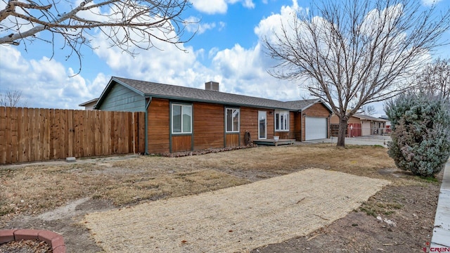 ranch-style house with a chimney, a shingled roof, an attached garage, and fence