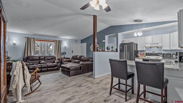 kitchen with high end fridge, under cabinet range hood, electric range oven, white cabinetry, and a peninsula