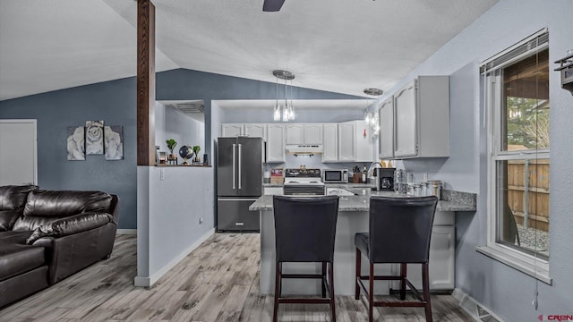 kitchen with a peninsula, stainless steel appliances, under cabinet range hood, white cabinetry, and light wood-type flooring