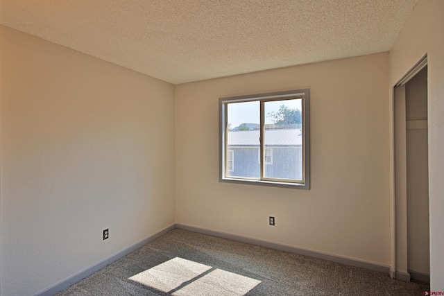 unfurnished bedroom featuring dark colored carpet, baseboards, and a textured ceiling