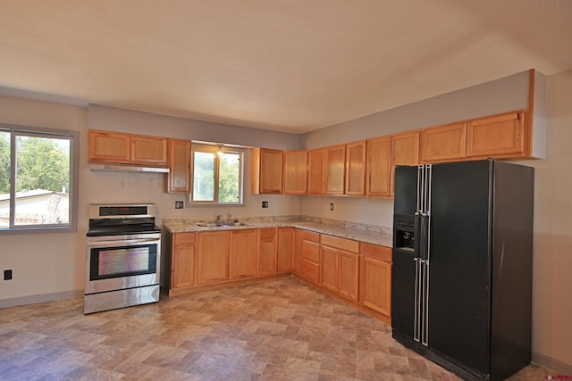 kitchen featuring baseboards, under cabinet range hood, light brown cabinetry, stainless steel electric range, and black refrigerator with ice dispenser