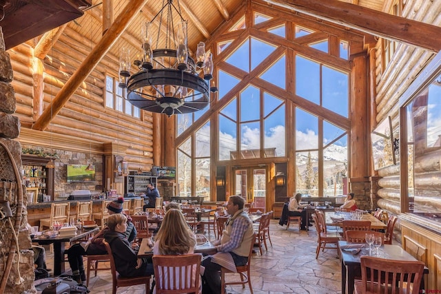 dining space with high vaulted ceiling, beam ceiling, stone tile flooring, wood ceiling, and a notable chandelier