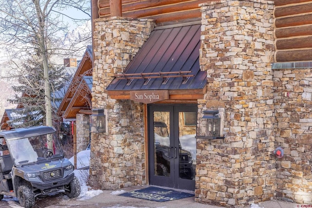 doorway to property featuring stone siding, french doors, metal roof, and a standing seam roof