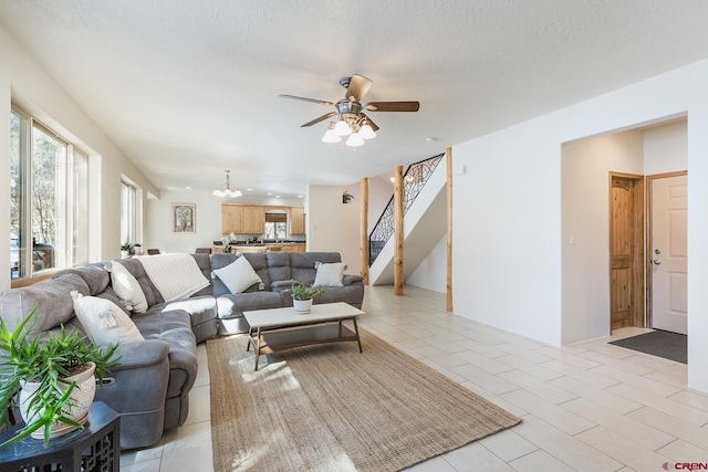 living area featuring light tile patterned floors, a textured ceiling, stairs, and ceiling fan with notable chandelier