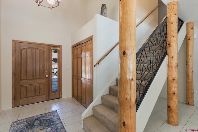 entryway with light tile patterned floors, stairway, and a towering ceiling