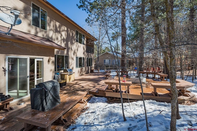 snow covered deck with a grill