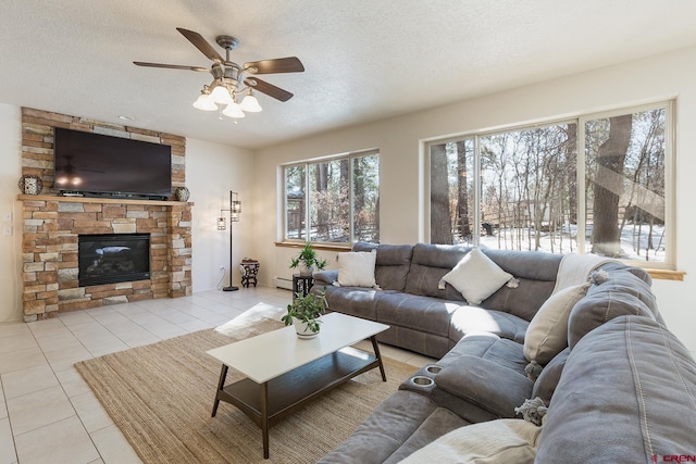 living room with light tile patterned floors, a ceiling fan, a fireplace, a textured ceiling, and a baseboard heating unit