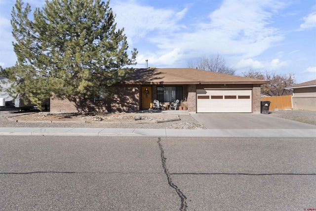 view of front of property with brick siding, concrete driveway, a garage, and fence