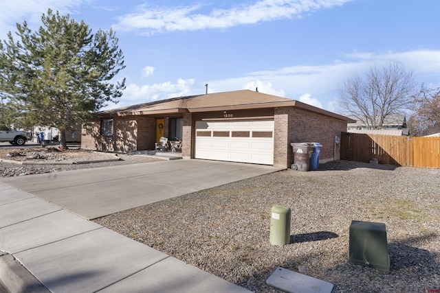 single story home featuring brick siding, concrete driveway, a garage, and fence