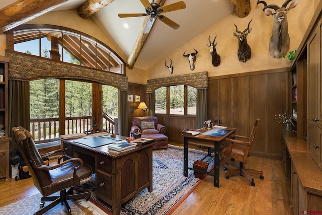 office area with beamed ceiling, a healthy amount of sunlight, a wainscoted wall, and light wood finished floors