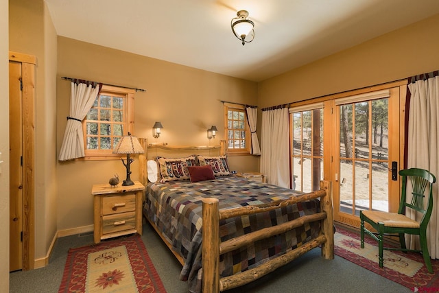 bedroom with dark colored carpet, baseboards, and access to exterior