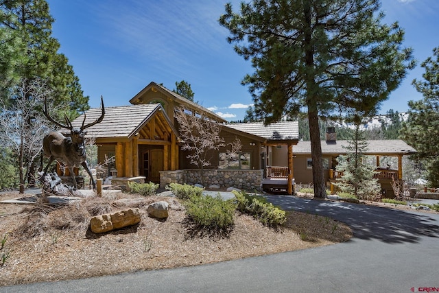 view of front of property featuring stone siding and a chimney