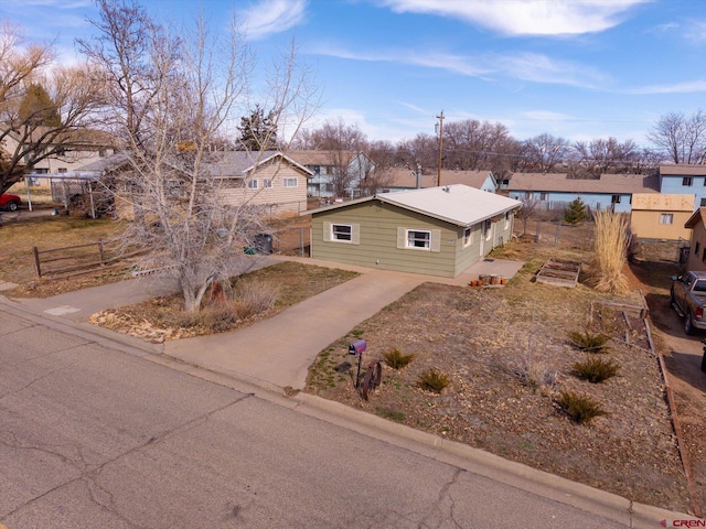 view of front facade with fence, a residential view, and driveway