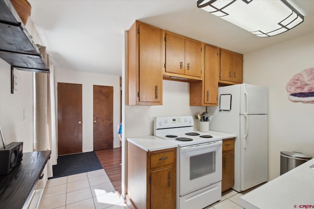 kitchen with light tile patterned flooring, brown cabinets, white appliances, and light countertops