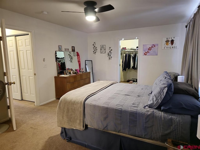 bedroom featuring light carpet, a ceiling fan, a closet, baseboards, and a spacious closet